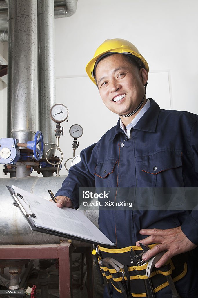 Worker checking the oil pipeline equipment Portrait of smiling worker with a clipboard checking the oil pipeline equipment in a gas plant, Beijing, China 50-54 Years Stock Photo