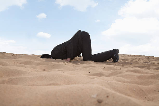 istock Young businessman kneeling with his head in the sand 459930755