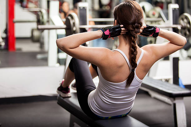 Pretty brunette doing crunches in front of a mirror in a gym