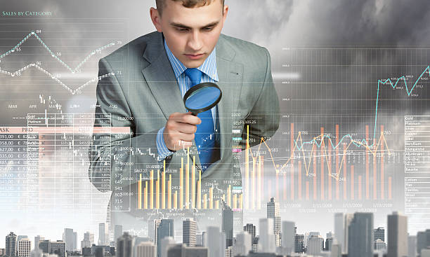 A man looking through a magnifying glass at a graph stock photo