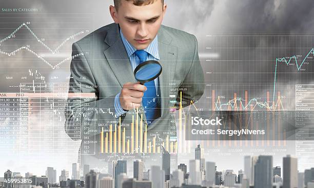 A Man Looking Through A Magnifying Glass At A Graph Stock Photo - Download Image Now