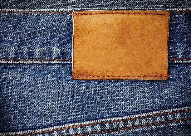 trama di jeans con etichetta di pelle con sfondo close-up - sewing denim textured close up foto e immagini stock