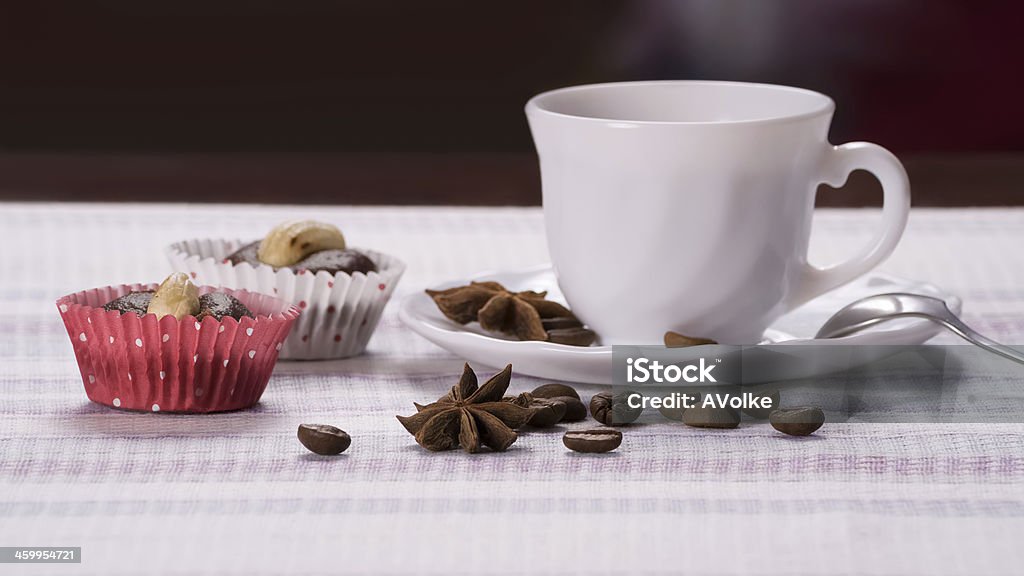 Cup of coffee decorated beans and star anise Cup of coffee decorated beans and star anise with fresh almond cakes on a striped napkin. Almond Stock Photo