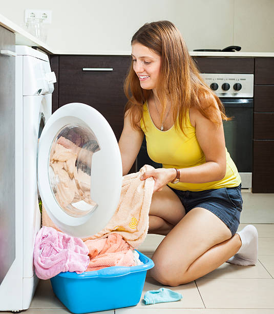 istock woman putting clothes in to washing machine 459957671