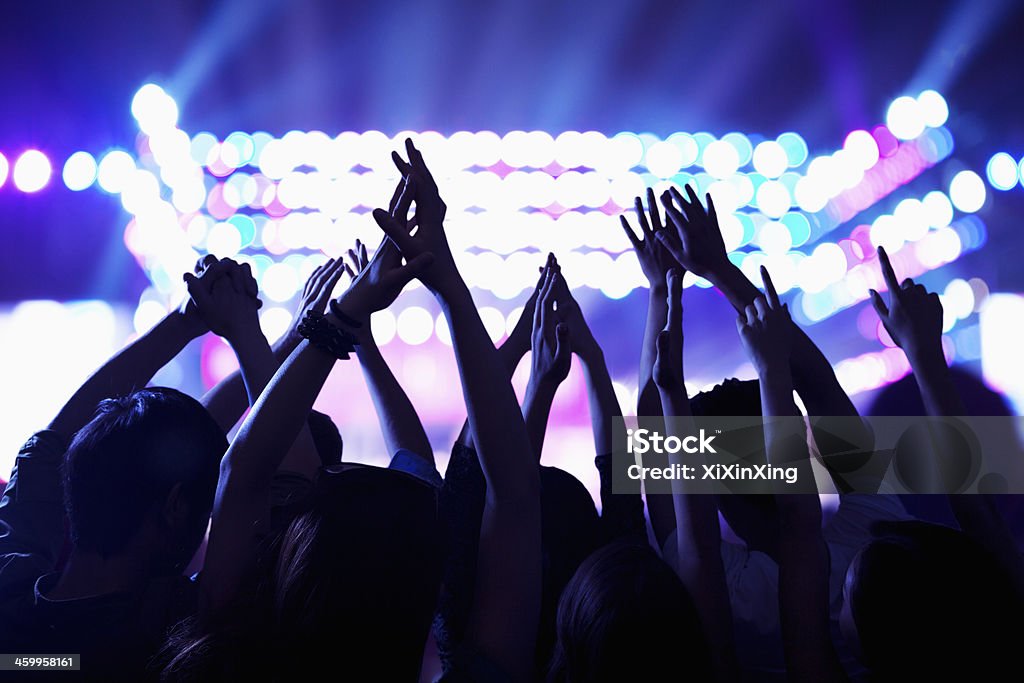 Audience watching a rock show, hands in the air Audience watching a rock show, hands in the air, rear view, stage lights Nightclub Stock Photo