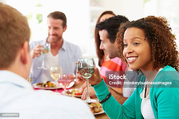 Group Of Friends Sitting Around Table Having Dinner Party Stock Photo - Download Image Now