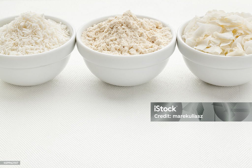 coconut flour and flakes coconut flour and flakes in three white ceramic bowls on white table cloth Flour Stock Photo