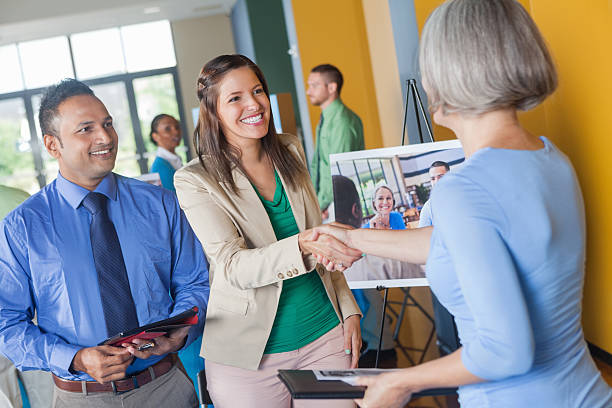 Woman shaking hands with professional executive at job fair event Woman shaking hands with professional executive at job fair event job fair stock pictures, royalty-free photos & images