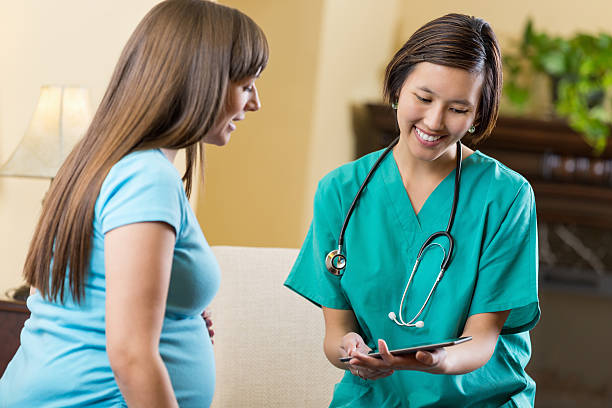 Pregnant patient consulting with doctor or midwife at home Pregnant patient consulting with doctor or midwife at home midwife photos stock pictures, royalty-free photos & images