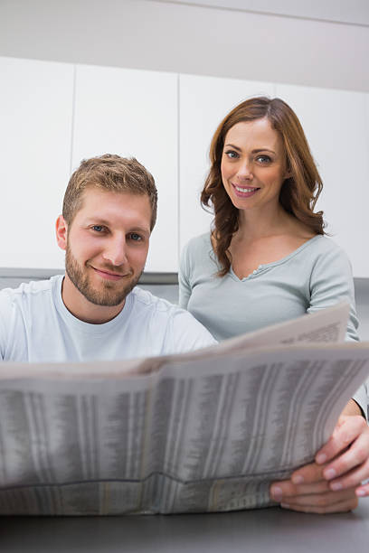 istock Smiling couple reading newspaper together in the morning 459965575