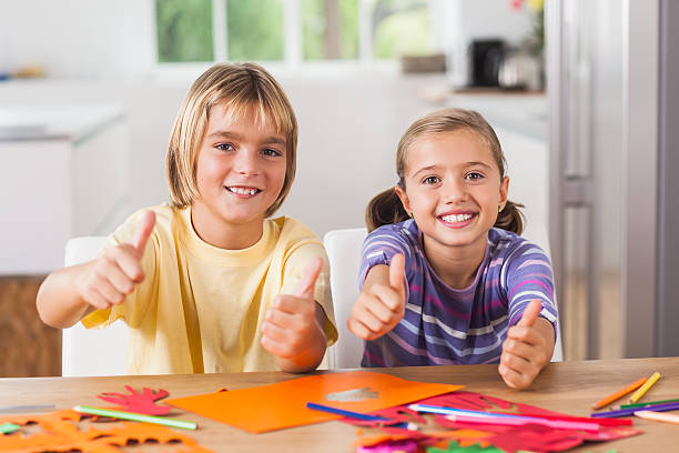 children giving thumbs up doing art and craft - boy and girl in kitchen thumbs up bildbanksfoton och bilder