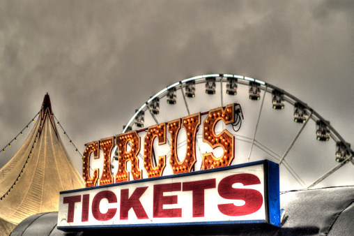 HDR image of a Circus Tickets sign with the big top in the background.