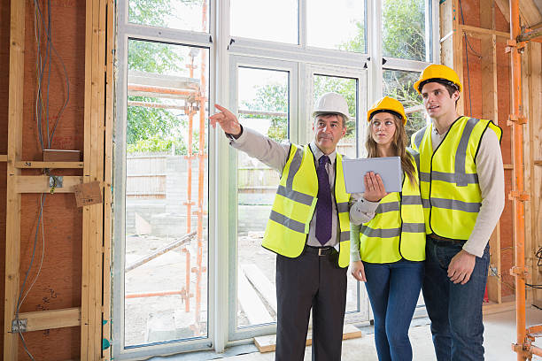 istock Architect pointing something out to couple in safety gear 459966979
