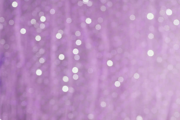 Horizontal abstract full frame studio shot of sequined mauve fabric with small blurred highlights.
