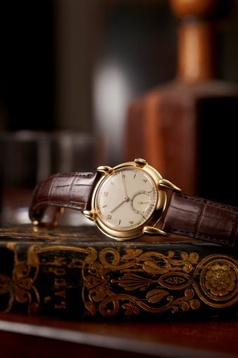 An antique gold watch on a gold leaf book
