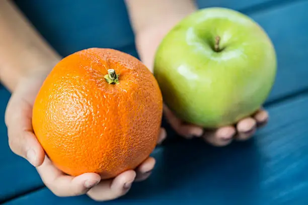 Child comparing apple to orange exhibiting the idea of comparing two completely different things