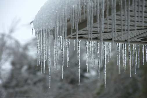 Icicles forming on the evestrough of a house after a winter ice storm.