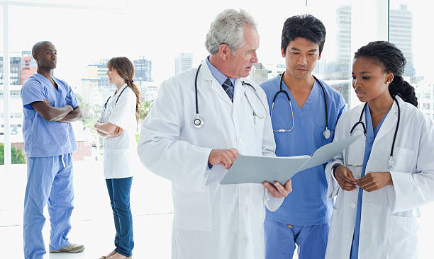 istock Doctor and two interns looking at files while their colleagues 459978547
