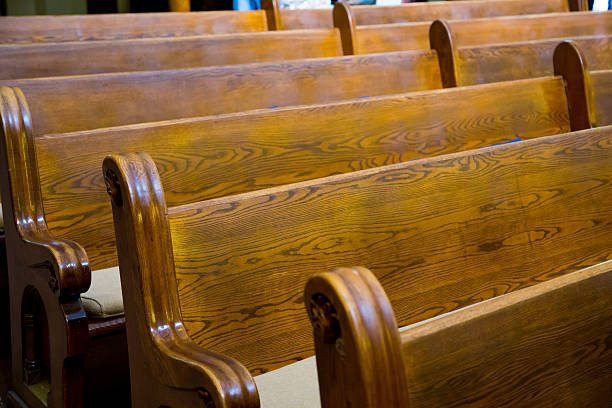 Five rows of old, wooden church pews stock photo