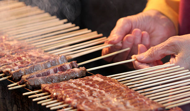 istock hand while turning the skewers of cooked meat 459980659