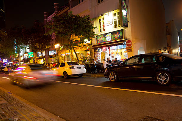 Singapore, singapore - September, 4th 2012: Night shot of street close to financial district with some traffic and night life at pubs and restaurants, Some people are sitting outside of festaurant in center of capture.
