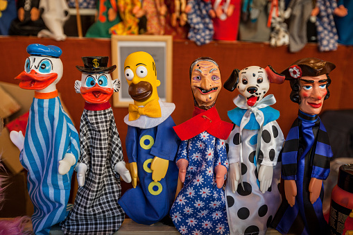 Rome, Italy - December 21, 2013: A collection of painted puppet, representing Simpson, Disney, and typical characters, sold in a small street vendor, during Christmas, in Rome at Piazza Navona.