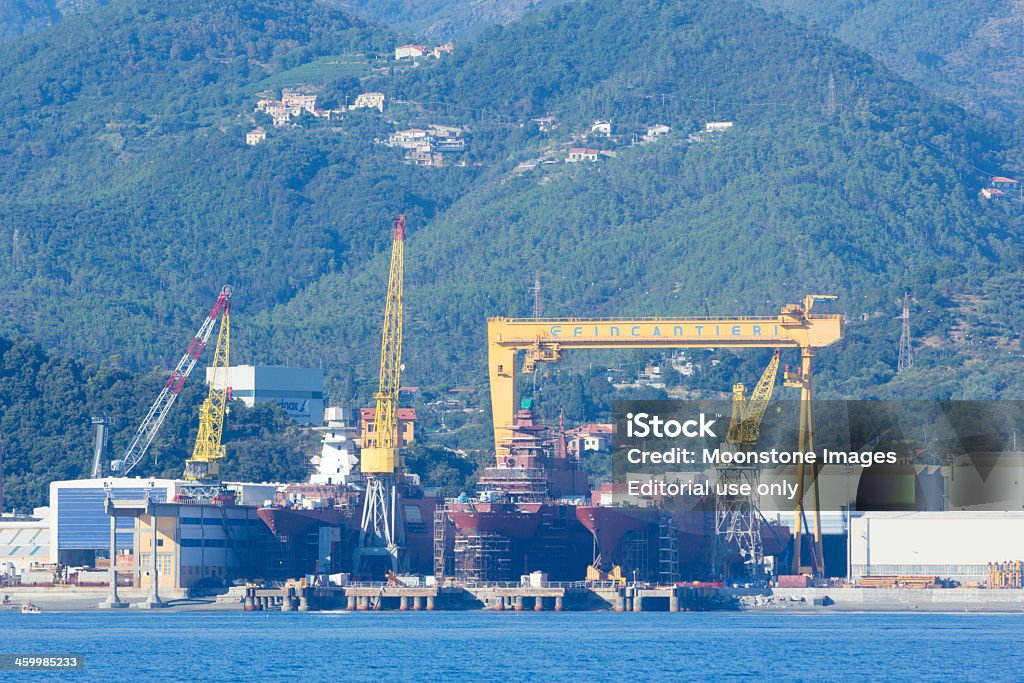 Riviera di Levante in Liguria, Italy Ligurian Sea, Italy - September 4, 2013: Development taking place on the coast of the Italian Riviera. In the image is an old shipyard, with cranes and identifiable logos and symbols. Built Structure Stock Photo