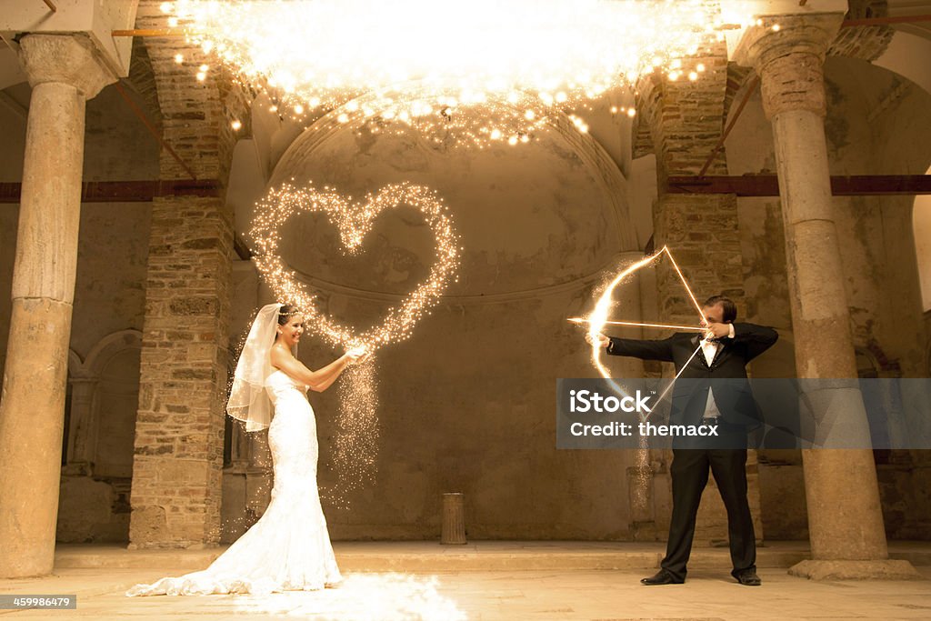 Bridge & Groom Dream Groom shooting in to heart of the bride. Magic effect with photoshop in the old church. Valentine's Day - Holiday Stock Photo