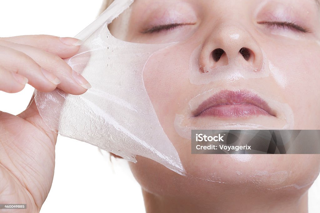 Portrait blond girl in facial mask. Beauty and skin care. Portrait of blond girl young woman in facial peel off mask. Peeling. Beauty and body skin care. Isolated on white background. Studio shot. Peel - Plant Part Stock Photo