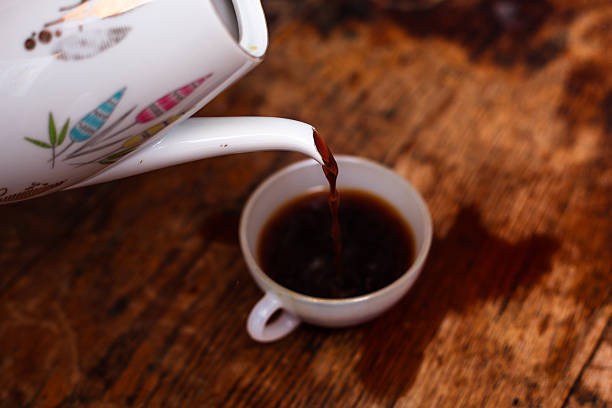 istock Coffee being poured into white china cup on wood table 460050251