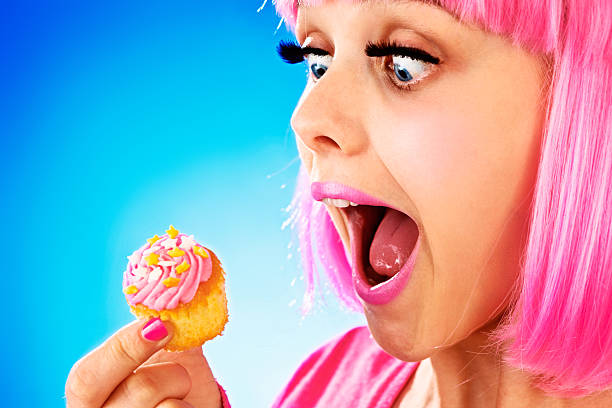 istock Pink-wigged cutie about to bite into cupcake 460062717