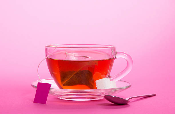 Cup with tea bag on saucer Cup with tea bag on saucer on pink background pink tea stock pictures, royalty-free photos & images
