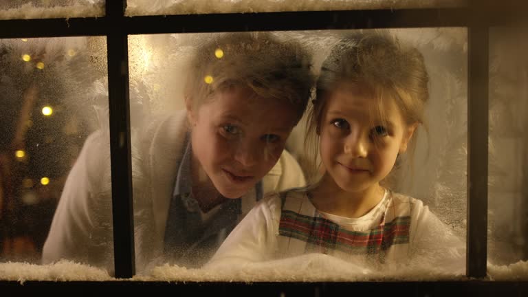 Kids looking out of the snowy window