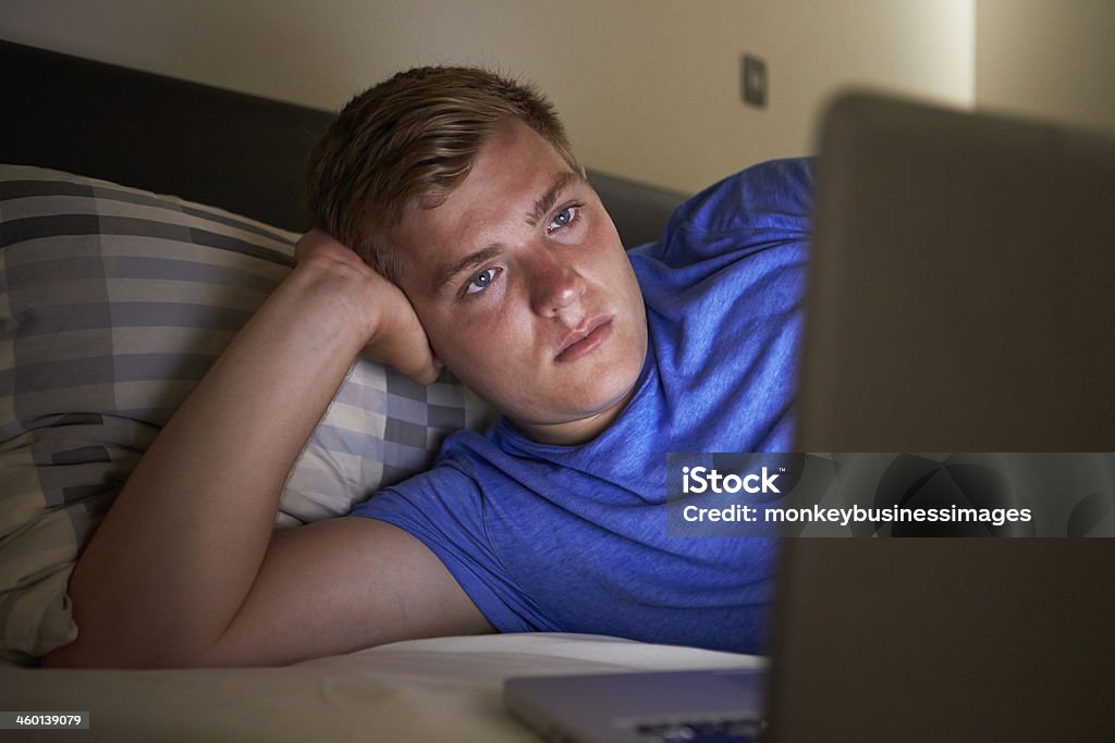 Teenage Boy Using Laptop In Bed At Night Teenage Boy Staying Up Using Laptop In Bed At Night Laptop Stock Photo
