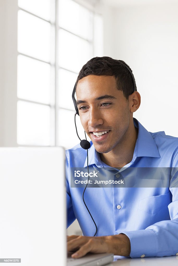 man wearing headset looking at monitor man wearing headset looking at computer monitor Call Center Stock Photo