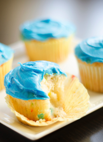 4 cupcakes on a plate with blue frosting