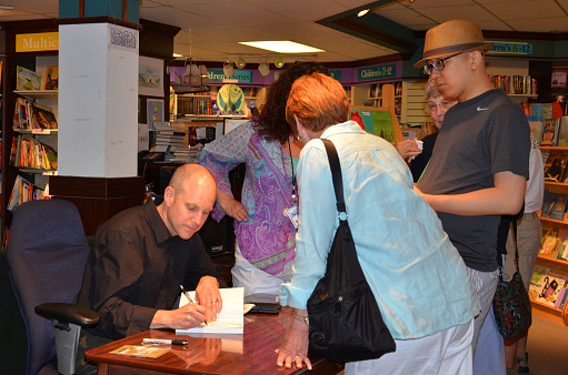 Ann Arbor, MI, United States - June 25, 2013: New York Times bestselling author Jim Ottaviani autographs a book  at a book signing for his new book 