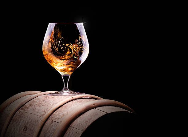 Glass of cognac or brandy on a barrel Cognac or brandy on a  black background cognac region photos stock pictures, royalty-free photos & images