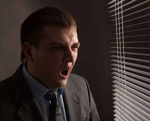 Tired office worker yawns in the late evening