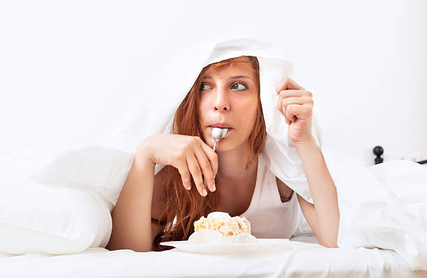 istock Woman with cake and spoon in bed 460257497