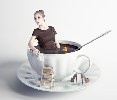 little beautiful woman takes a bath in cup of coffee (creative concept)