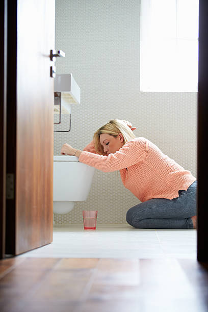 A young woman resting by a toilet in the bathroom Teenage Girl Feeling Unwell In Bathroom Kneeling By Toilet nausea photos stock pictures, royalty-free photos & images