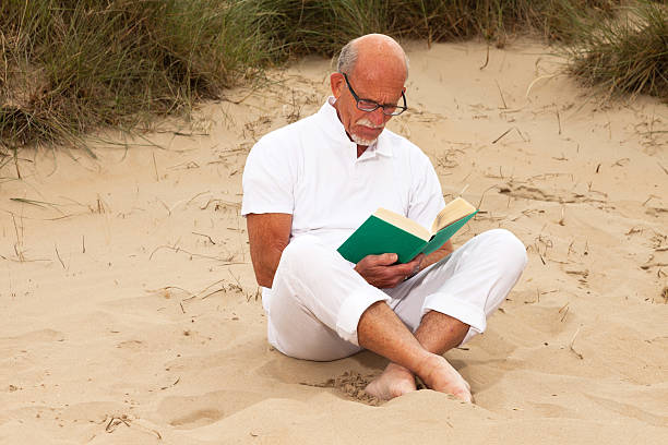 istock Retired man with beard and glasses reading a book. 460314123