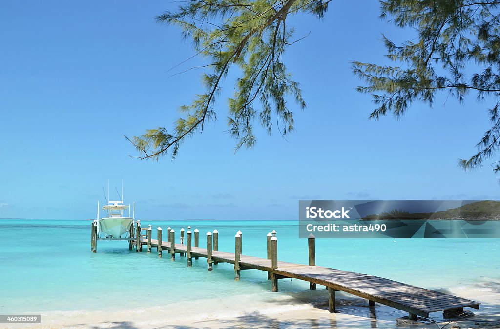 Wooden pier in the Bahamas with boat in background Yacht at the wooden jetty. Exuma, BahamasWooden pier. Exuma, Bahamas Exuma Stock Photo