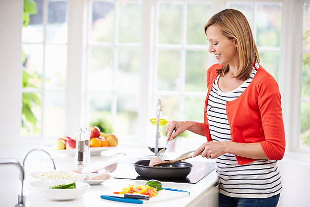 istock Woman Standing At Hob Preparing Meal In Kitchen 460315377