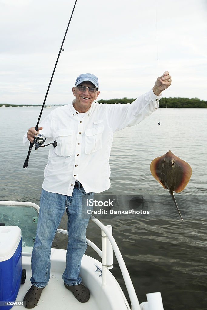 Uomo anziano pesca catture di una Pastinaca - Foto stock royalty-free di 70-79 anni