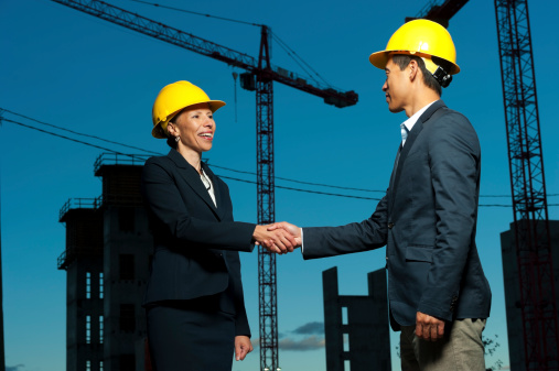 Two business people shake hands at a Construction site