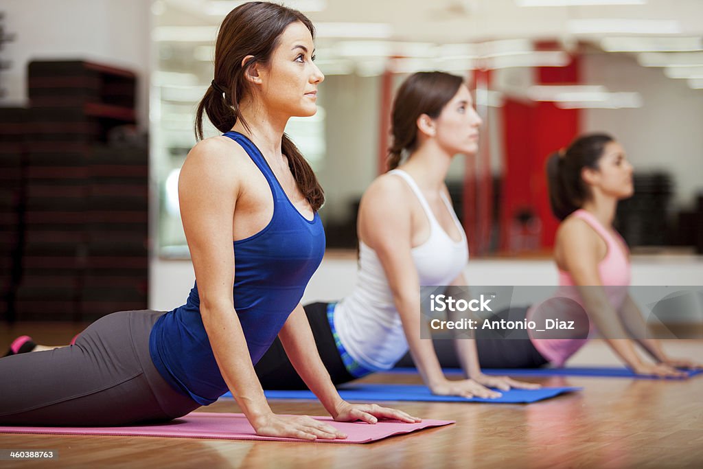 Working on the cobra yoga pose Cute Hispanic women practicing the cobra pose during their yoga class in a gym Yoga Class Stock Photo