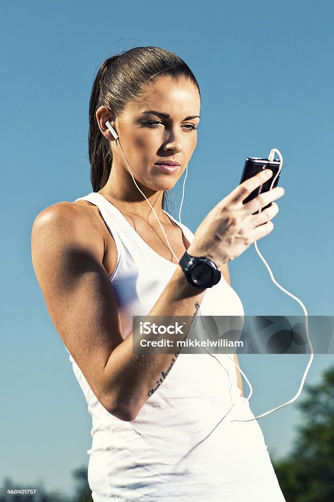 Donna in vestiti fittness tiene un telefono cellulare - Foto stock royalty-free di Abbigliamento sportivo