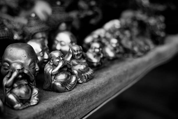 Small Buddha statues for sale on the shelf, closeup black and white